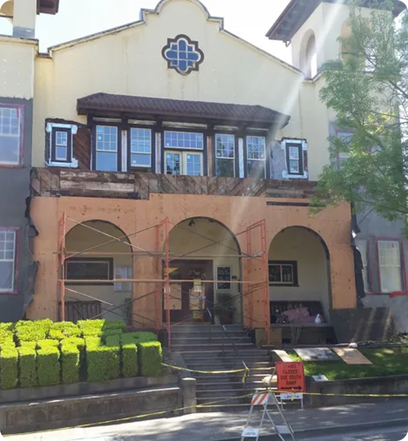 A building under renovation with scaffolding around the entrance and caution tape blocking the stairs. A "closed" sign is visible at the bottom.